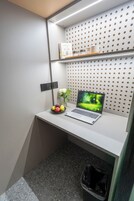A small workspace with a laptop, a bowl of fruit, and a vase with flowers.