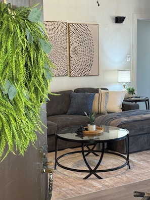 Una sala de estar con un sofá, una mesa de centro y decoración en la pared.
