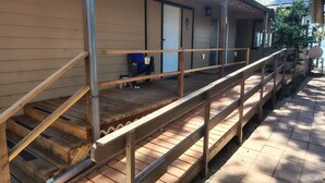 A wooden deck with a railing, a door, and a small outdoor seating area.