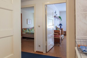 Una habitación con una cama, un escritorio y una silla, con una puerta que da a otra estancia.