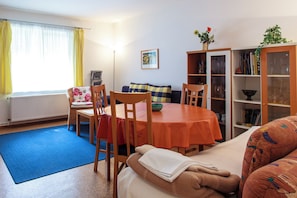 A cozy living room with a dining table, chairs, a sofa, and a bookshelf. - A peaceful place to stay in Berlin's green north | 58 m² | up to 4 people | garden view (Berlin)