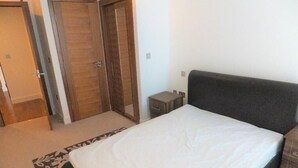 A bedroom with a bed, a nightstand, a dresser, and two doors. - Spacious 2 Bedroom Apartment in the Heart of the City (Cardiff)