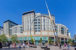 A modern building with a curved facade, multiple floors, and a prominent sculpture in the center. - Spacious 2 Bedroom Apartment in the Heart of the City (Cardiff)