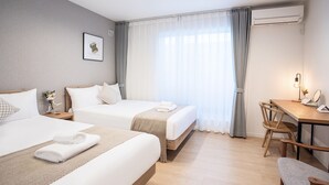 Ein Hotelzimmer mit zwei Betten, einem Schreibtisch, einem Stuhl und einer Klimaanlage.