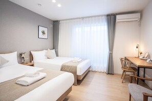 A hotel room with two beds, a desk, a chair, and an air conditioning unit. - SHOTENSHITA (Osaka)