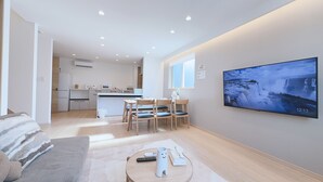 Ein modernes Wohnzimmer mit Fernseher, Sofa und Essbereich.