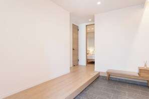 A hallway with a bench, a wooden door, and a small table with a candle. - SHOTENSHITA (Osaka)