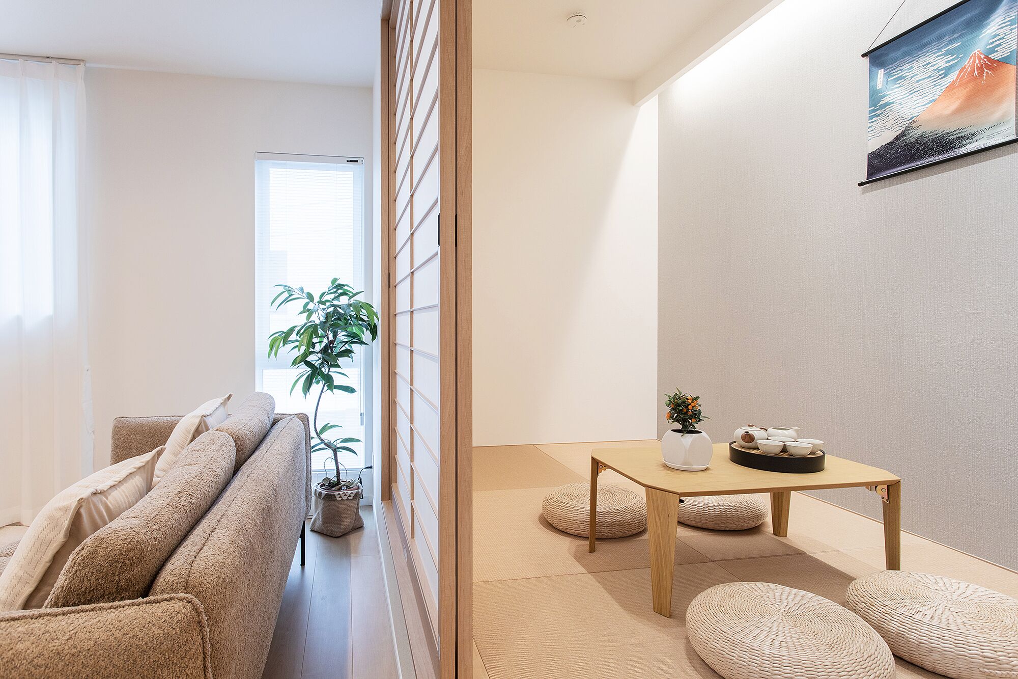 A room with a sofa, a table with tea set, a plant, and a painting on the wall.