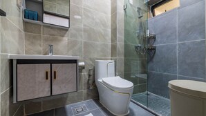A modern bathroom with a glass shower enclosure, a toilet, and a sink. - Shamms smarthome Studio 2 (Nairobi)