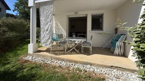Ein weißes Gebäude mit Balkon, Tisch und Stühlen sowie einem Fenster.