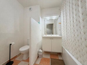 Ein Badezimmer mit Toilette, Waschbecken, Spiegel und Wandpapier mit Muster.