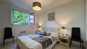 Ein Schlafzimmer mit einem Bett, zwei Nachttischen, einem Fenster und einer Deckenleuchte.