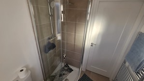 Ein Badezimmer mit Duschkabine, Toilette, Handtuchhalter und Heizkörper.