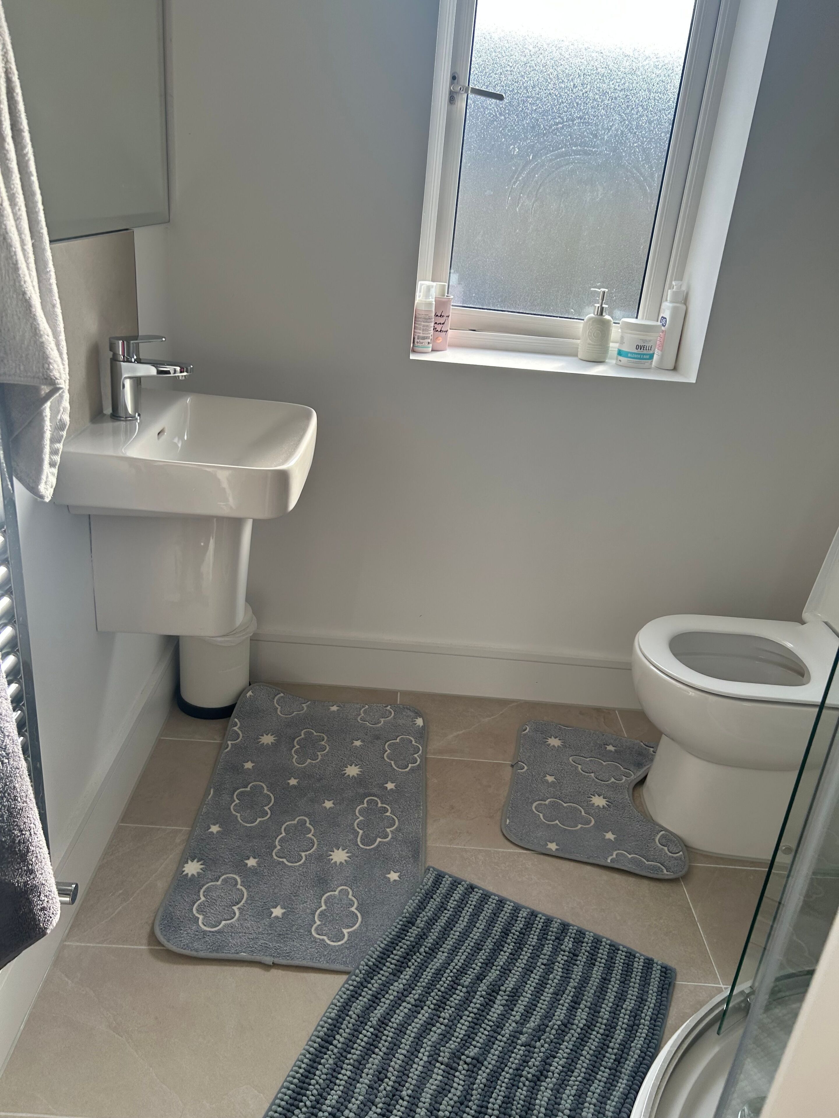 A bathroom with a sink, toilet, and window.