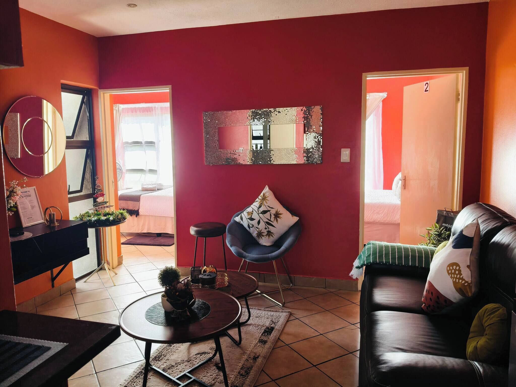 A living room with a red wall, a round table, a sofa, and a mirror.