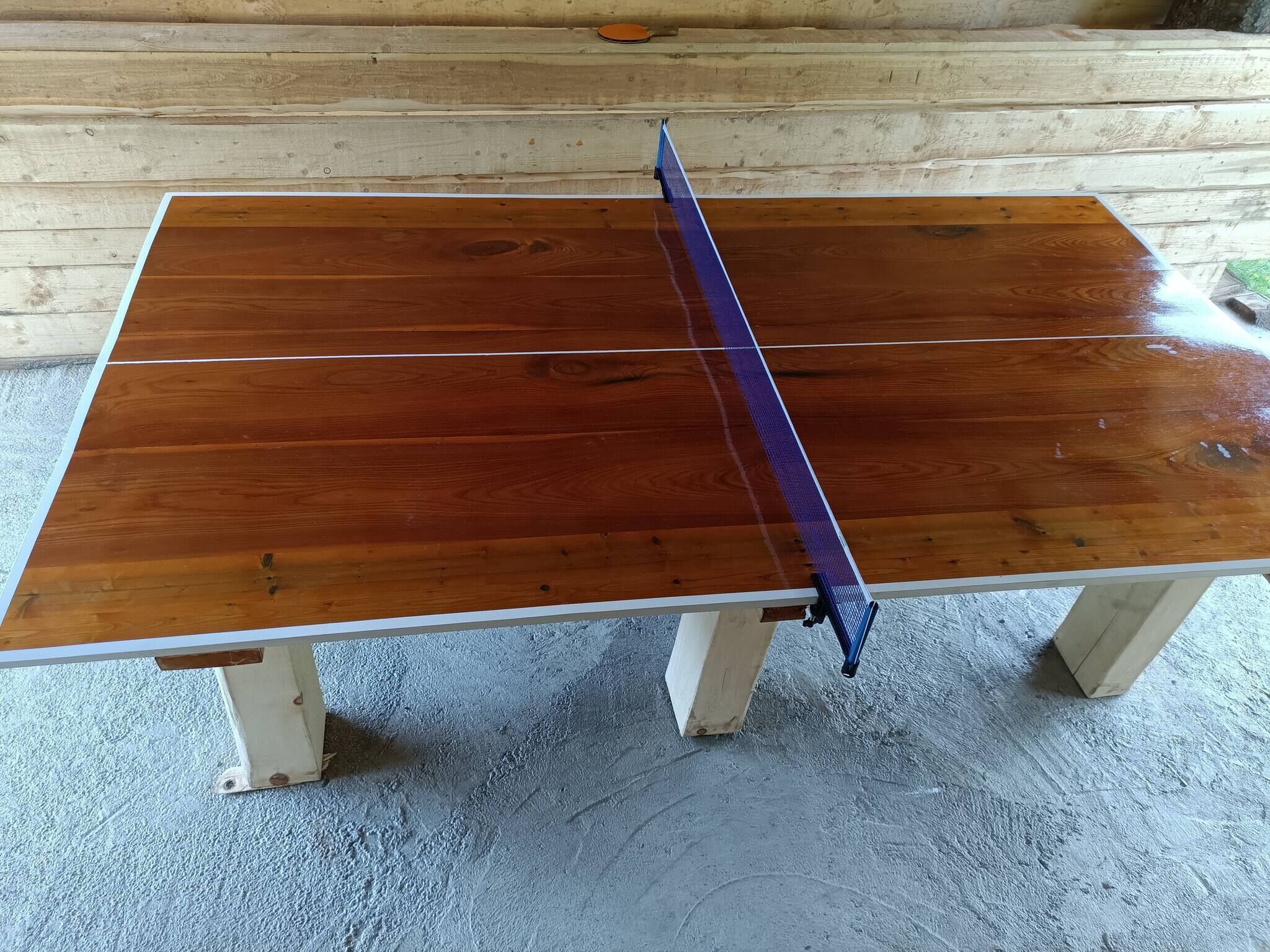 Ein Holztisch mit einem blauen Netz, vor einer Holzwand platziert.