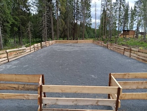 An outdoor riding arena with wooden fences and a gravel surface.