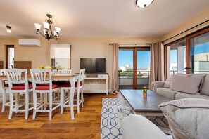 Ein modernes Wohnzimmer mit Essbereich, einem Flachbildfernseher und einem Balkon mit Blick.