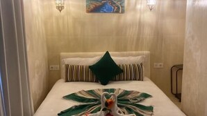 Une chambre d’hôtel avec un lit, un tableau, deux lampes fixées au mur et une composition décorative faite de serviettes.