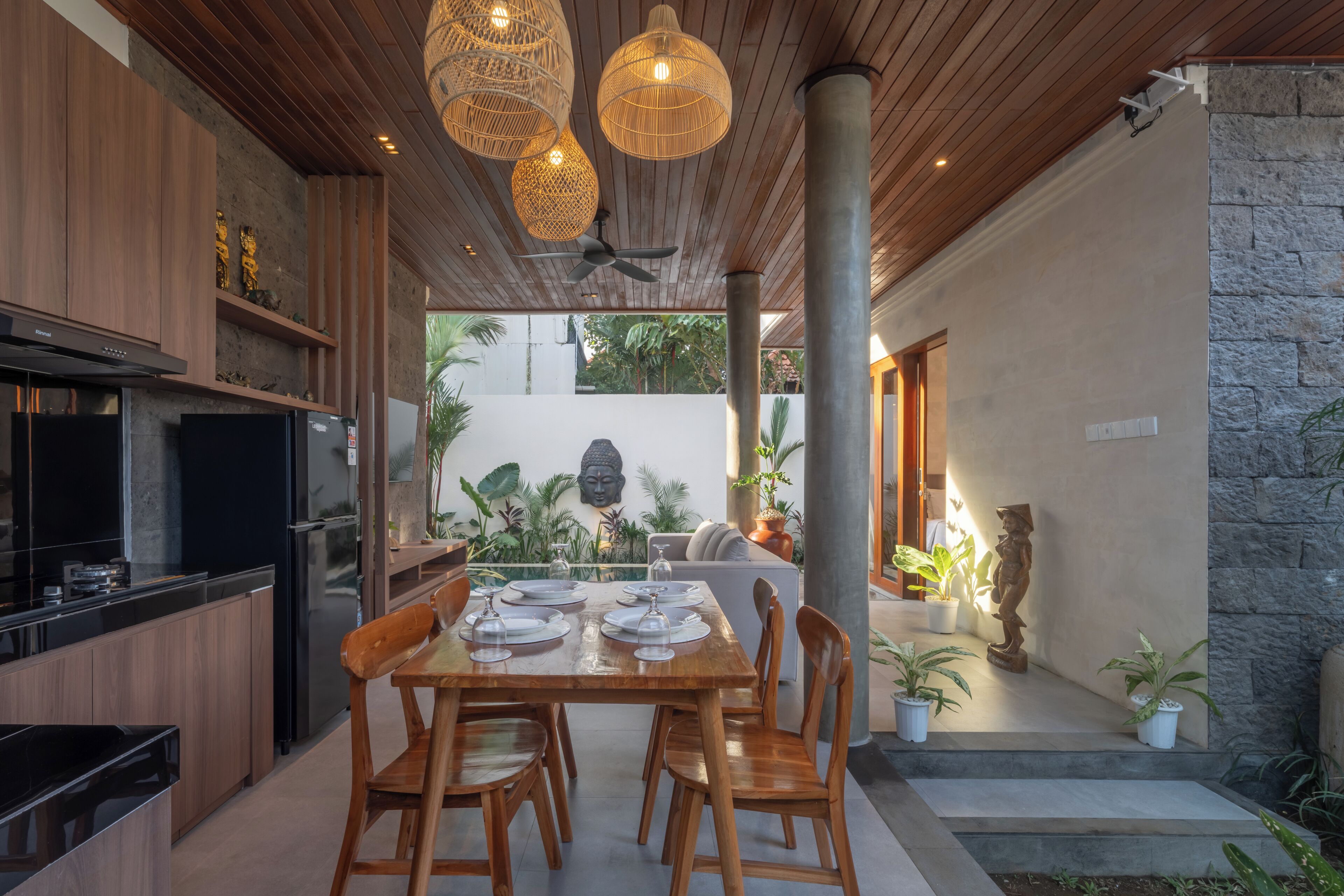 Una cucina moderna con mobili in legno, piano cottura integrato e zona pranzo con tavolo e sedie in legno.