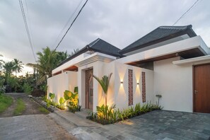 Una casa moderna con entrada pavimentada, puerta de madera y jardín bien cuidado.