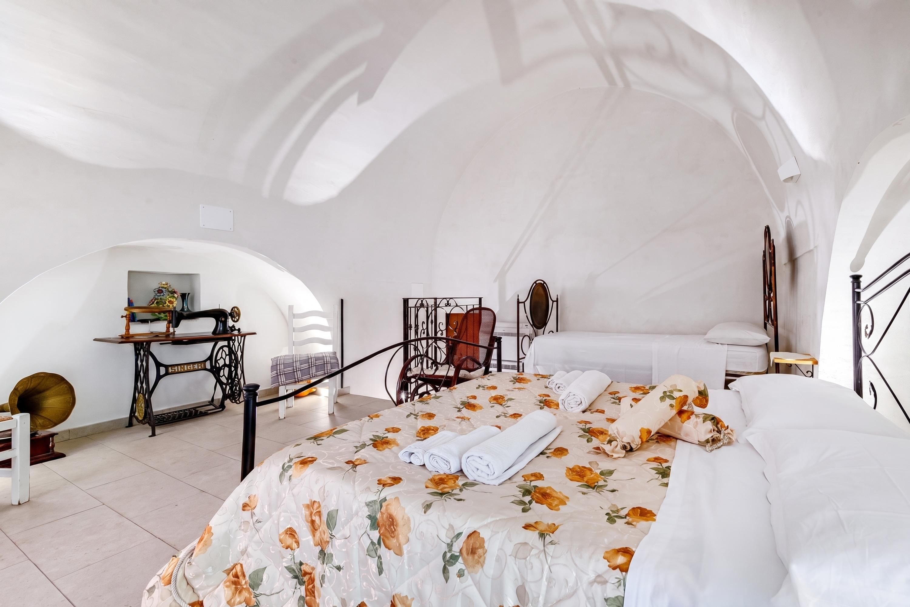 Een kamer met een bed, een naaimachine, een stoel en een tafel.