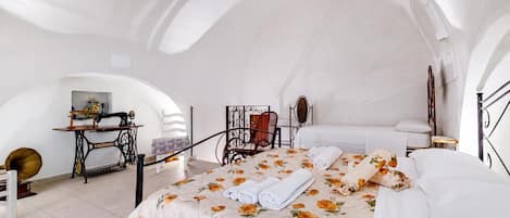 A room with a bed, a sewing machine, a chair, and a table.