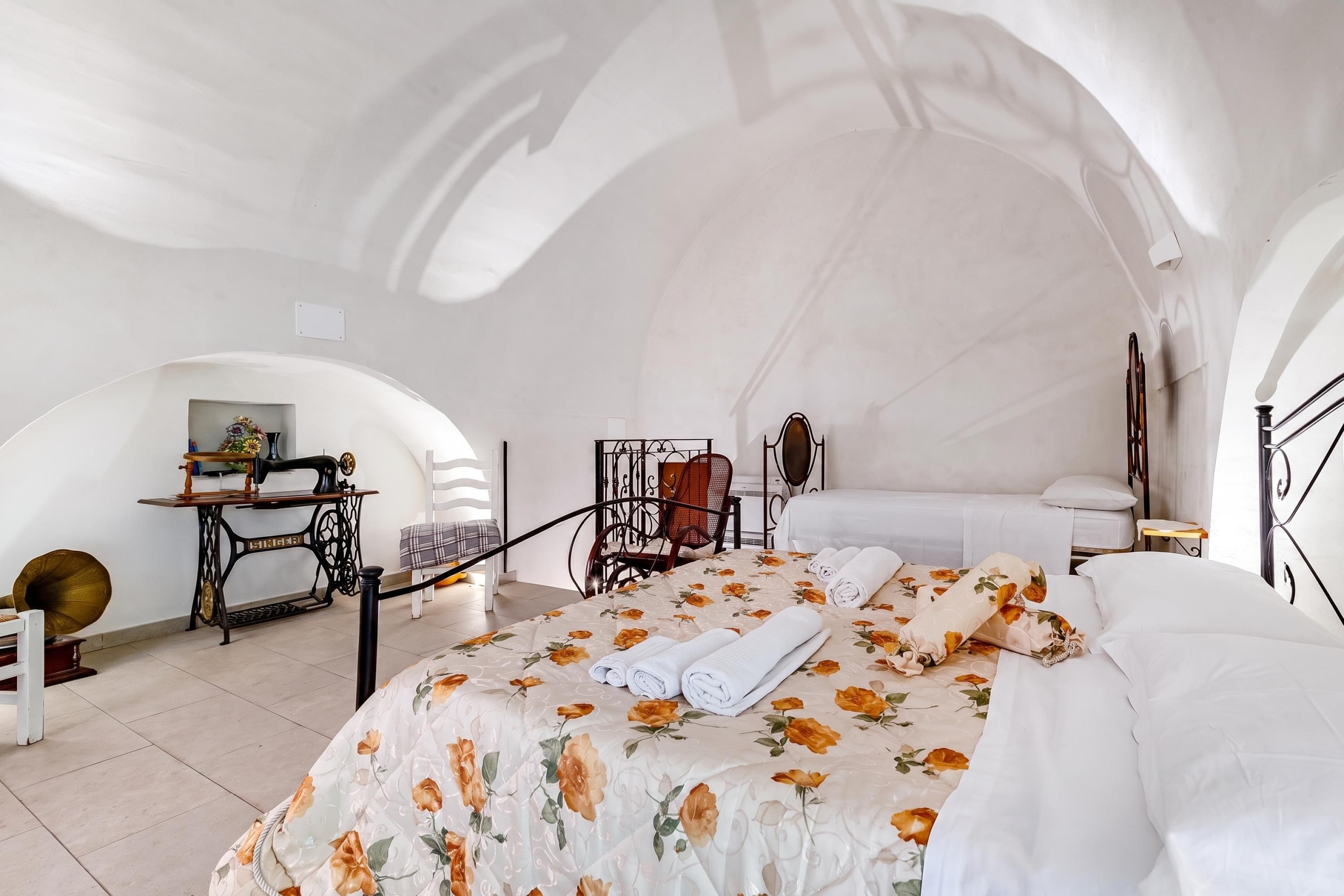 Una camera da letto con un letto, una macchina da cucire, una sedia e un tavolo.