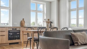 A modern kitchen with a dining area, a sofa, and a view of the outdoors.