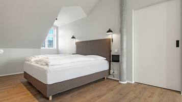 A bedroom with a bed, a window, a ceiling light, and a door.