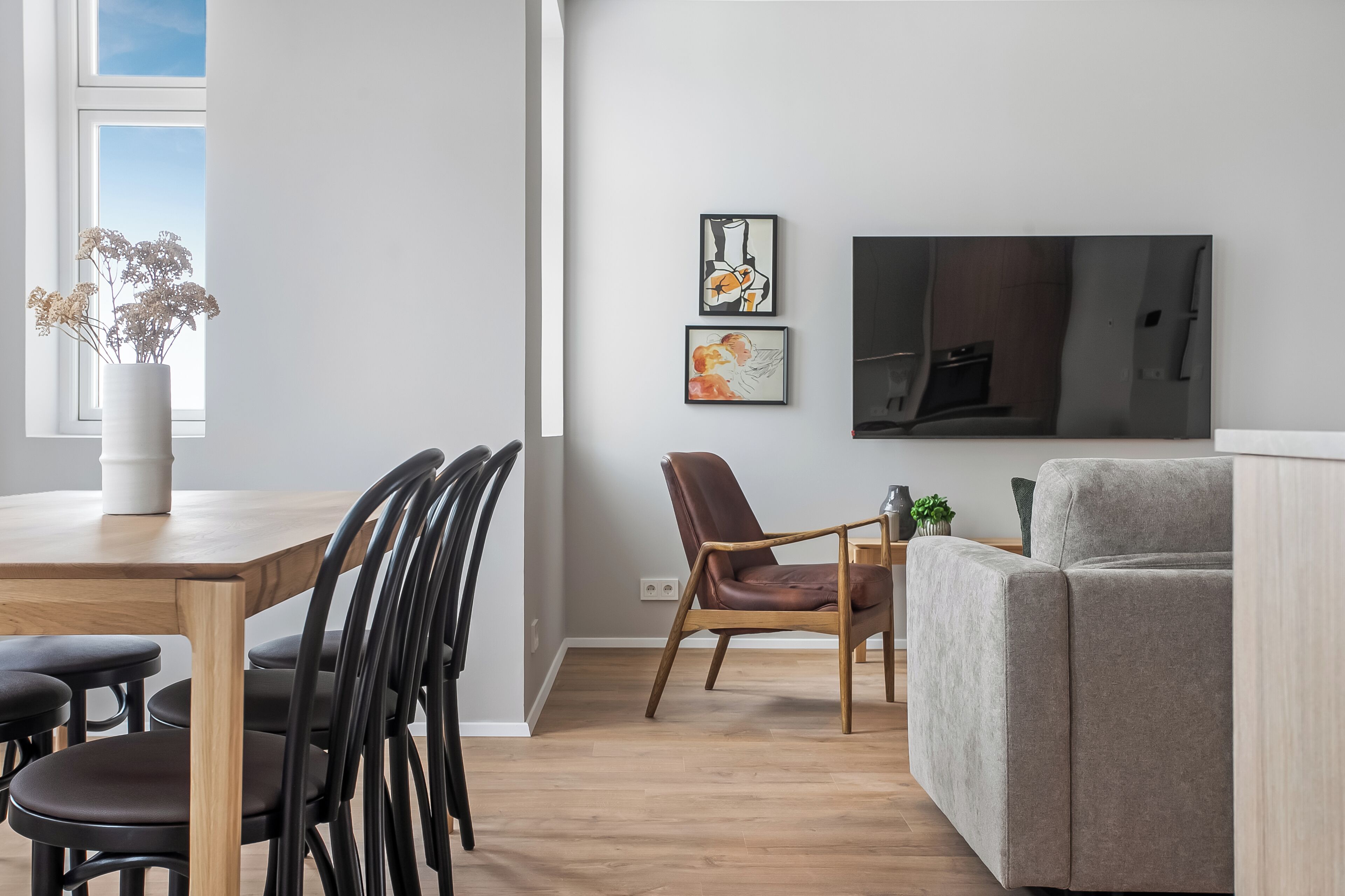 Una sala de estar moderna con comedor, un sofá, un televisor y obras de arte en la pared.