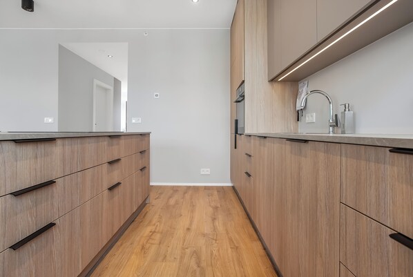 A modern kitchen with wooden cabinets, a stainless steel sink, and a countertop.