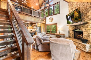 A spacious living area with a fireplace, a dining table, and a comfortable seating arrangement. - Mt View, Spa, Firepit, EV Chrgr & Pvt Riverside Pk (Blue Ridge)