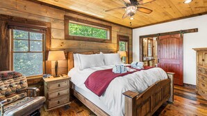 A wooden bedroom with a bed, nightstands, a chair, a dresser, and a ceiling fan. - Mt View, Spa, Firepit, EV Chrgr & Pvt Riverside Pk (Blue Ridge)