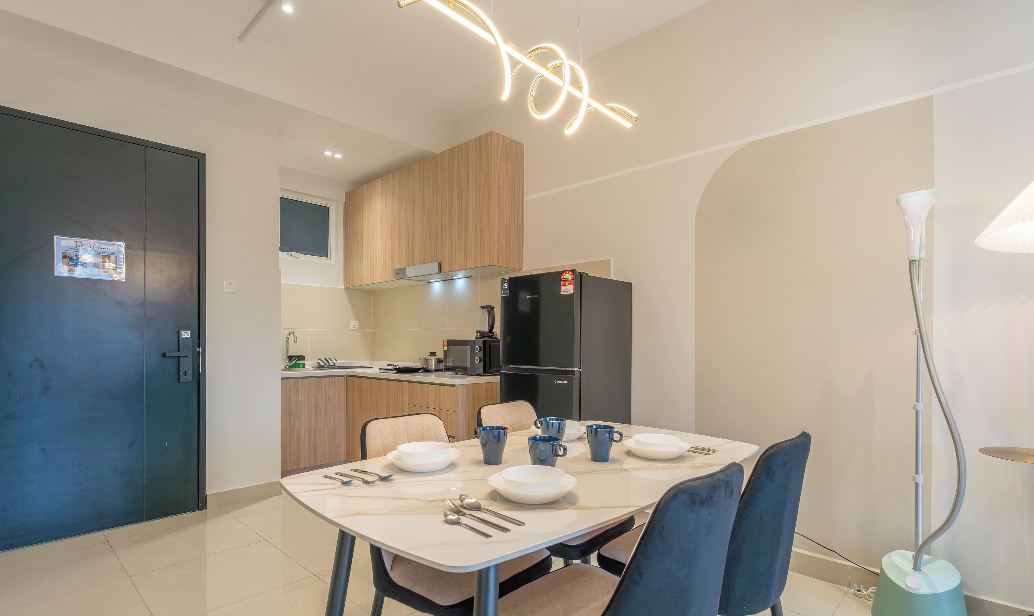 Une cuisine moderne avec un réfrigérateur noir, des armoires en bois et un coin repas avec une table dressée pour deux personnes.