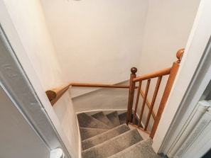 Eine Teppich-Treppe mit Holzhandläufen und einer weißen Wand.