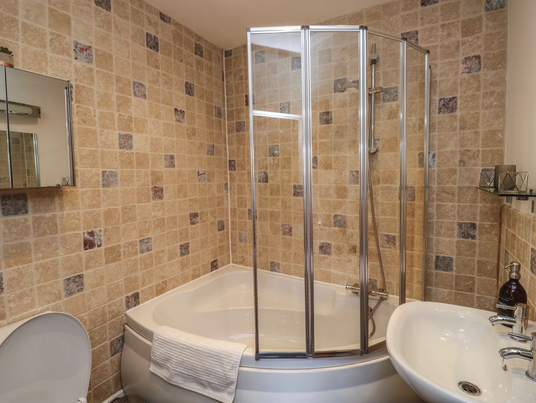 A bathroom with a glass shower enclosure, a bathtub, a toilet, and a sink.