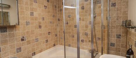 A bathroom with a glass shower enclosure, a bathtub, a toilet, and a sink.