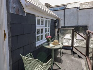 A small outdoor seating area with a table and chairs, a window with a view, and a staircase leading to an upper level. - Top Storey (Dartmouth)