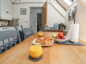 A dining table with croissants, apples, and orange juice in a modern kitchen with a view of the sky. - Top Storey (Dartmouth)