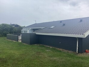 A residential building with a sloped roof, a small attached structure with a window, and a fenced yard. - 4 Star Holiday Home in Harboore (Harboore)