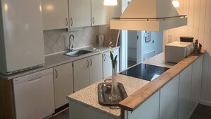 A kitchen with white cabinets, a sink, a stove, and pendant lighting. - 4 Star Holiday Home in Harboore (Harboore)