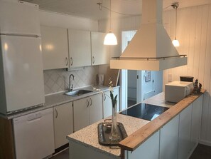 A kitchen with white cabinets, a sink, a stove, and pendant lighting. - 4 Star Holiday Home in Harboore (Harboore)