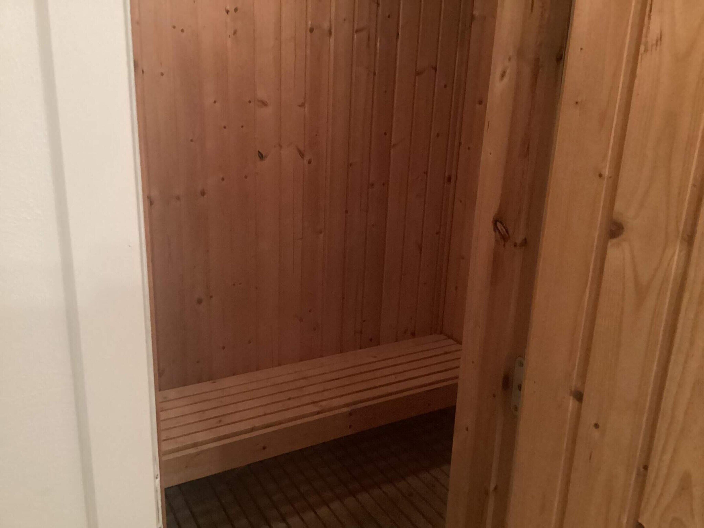 A wooden sauna with a bench and a tiled floor.
