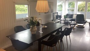 A modern dining area with a long table, chairs, a TV, and a decorative vase. - 4 Star Holiday Home in Harboore (Harboore)