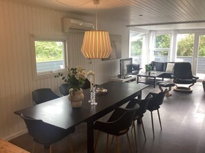 A modern dining area with a long table, chairs, a TV, and a decorative vase. - 4 Star Holiday Home in Harboore (Harboore)