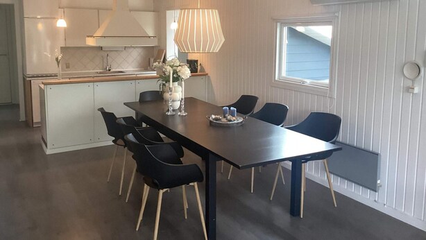 A modern kitchen with white cabinets, a dining area with a dark table and chairs, and a window with a view. - 4 Star Holiday Home in Harboore (Harboore)