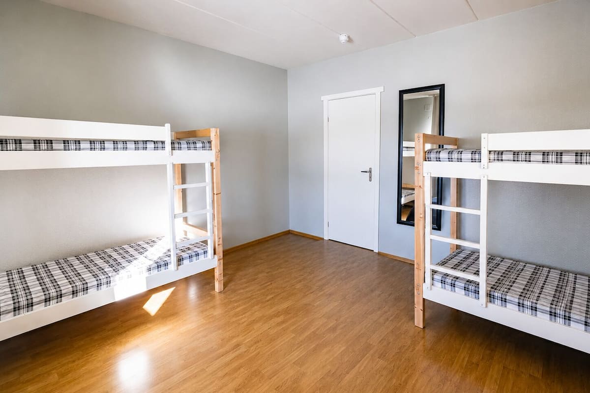 Una habitación con dos literas, una puerta y un espejo.