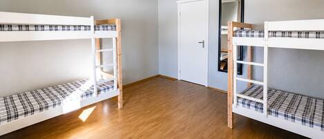 Una habitación con dos literas, una puerta y un espejo.