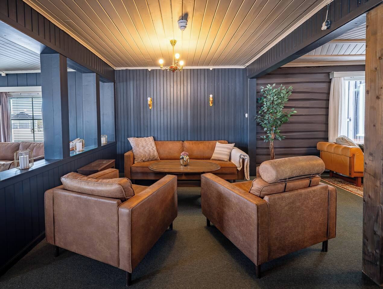 Une pièce avec un plafond en bois, un canapé en cuir marron et une table basse ronde.
